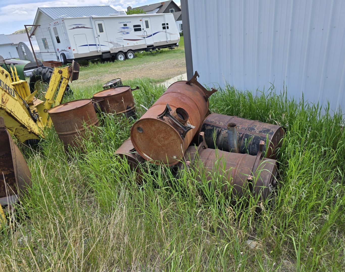 100-gallon metal drums and tractor arm hauled for commercial junk removal in Park County, WY—Good Junk Removal services.