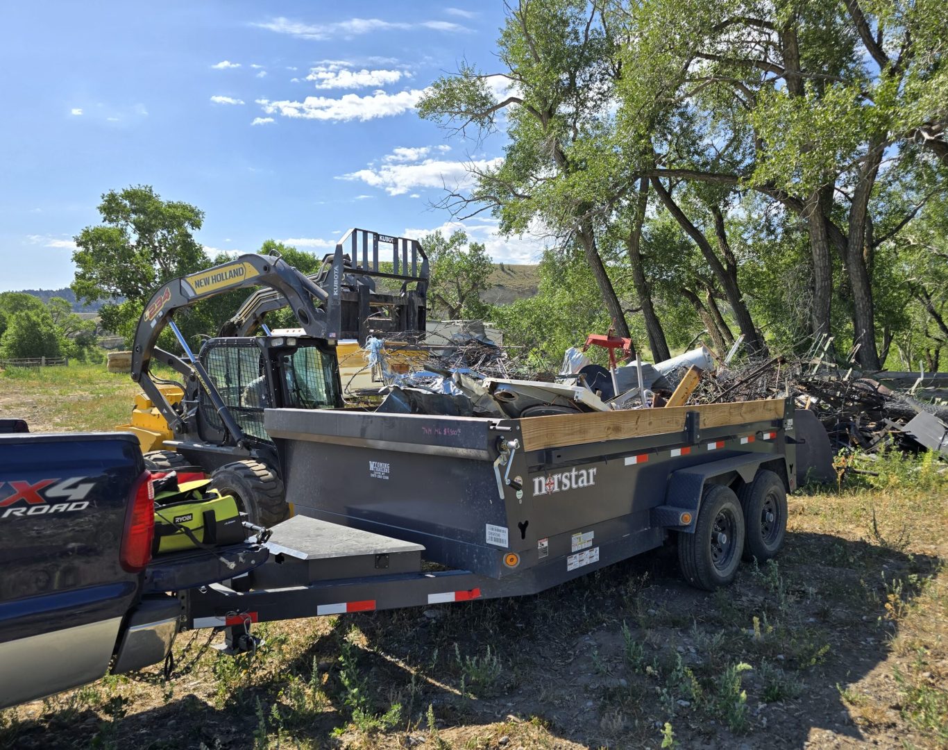 Big pile of ranch metal scrap and slide-in truck camper loaded for commercial junk removal in Park County, WY—Good Junk Removal.